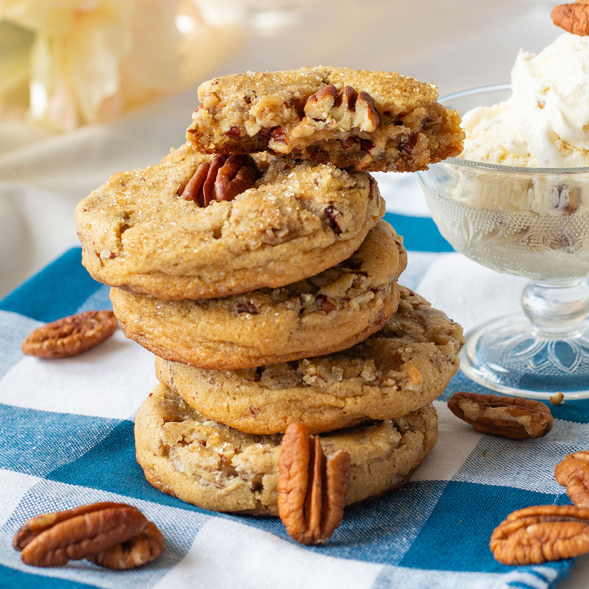 Multiple butter pecan cookies stacked next to a bowl of ice cream