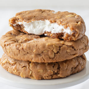 Three Oatmeal Cream Pie Cookies—one split open to reveal its rich, creamy filling inside.