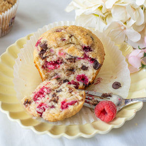 A delicious looking image of a Jumbo Raspberry Chocolate Chip Muffin with a bite taken out of it, showcasing the soft, moist texture and the burst of raspberry and chocolate flavors inside.