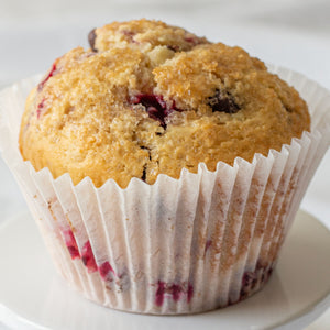 A close-up image of a Jumbo Raspberry Chocolate Chip Muffin with visible chunks of raspberries and chocolate chips on top.