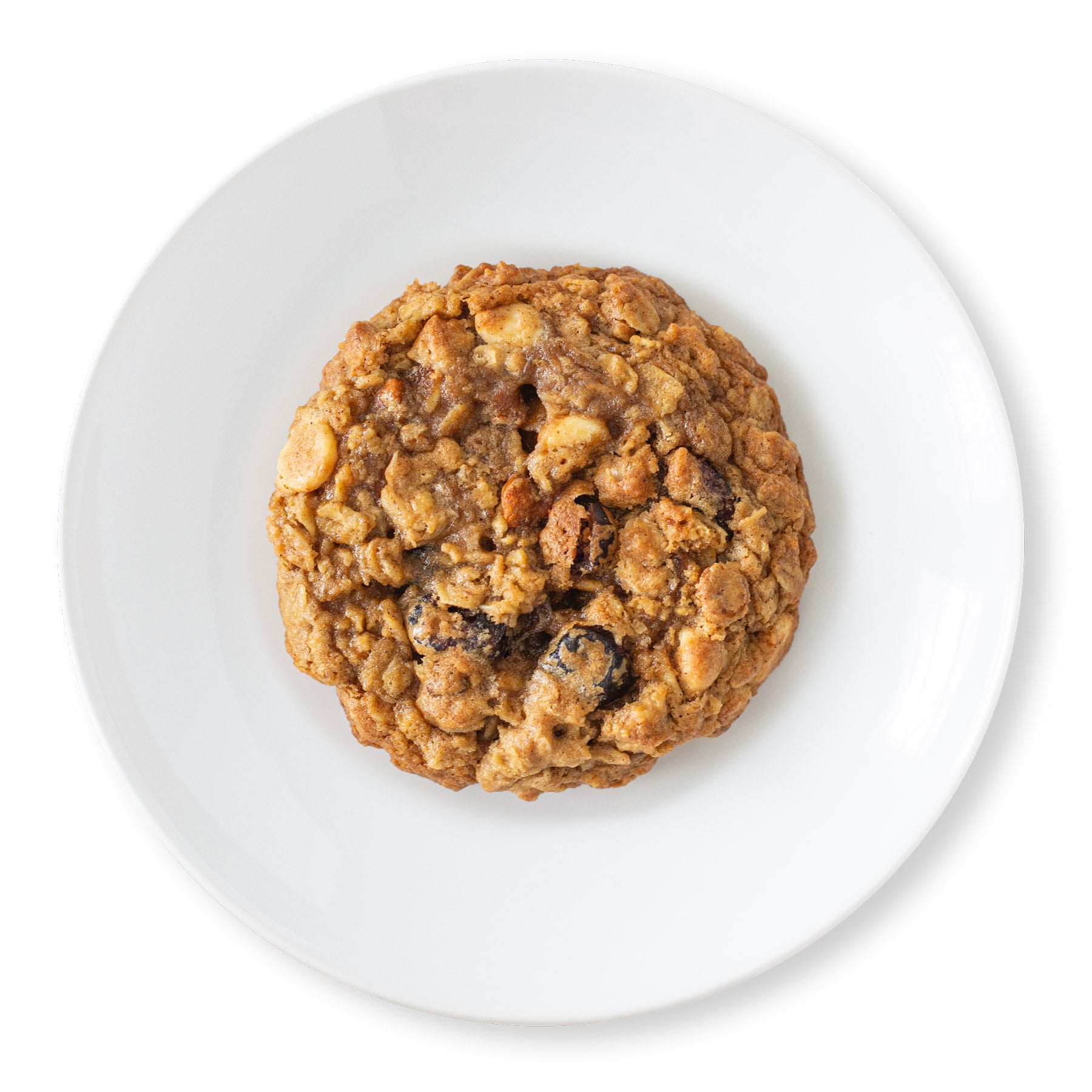 Top-down view of a Spiced Pumpkin Oat Cookie, showcasing a golden-brown, rustic texture with visible oats, dried cranberries, and melted white chocolate and cinnamon chips.