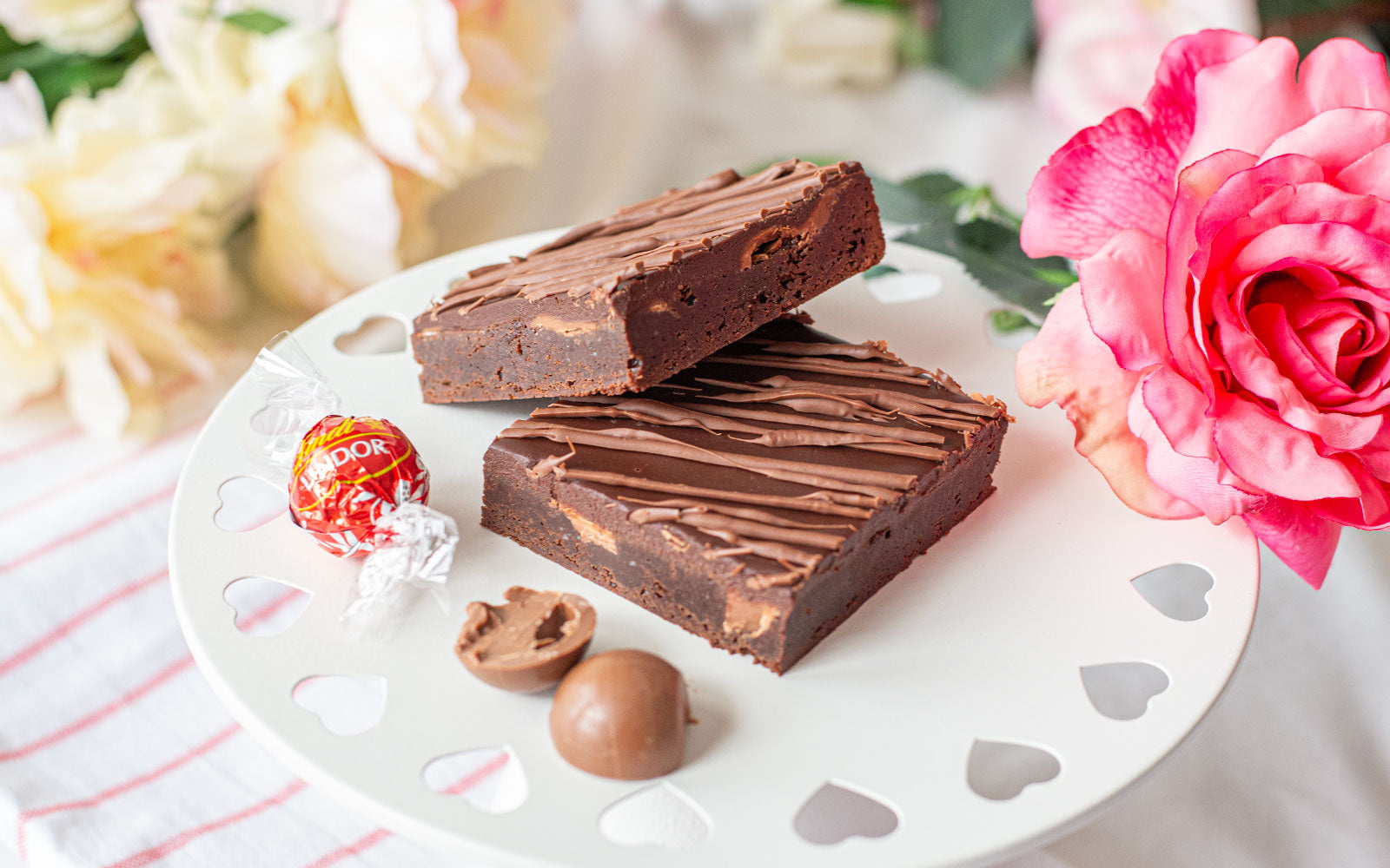 Picture of two decadent Triple Chocolate Truffle Brownies on a tray with a chocolate truffle next to them.